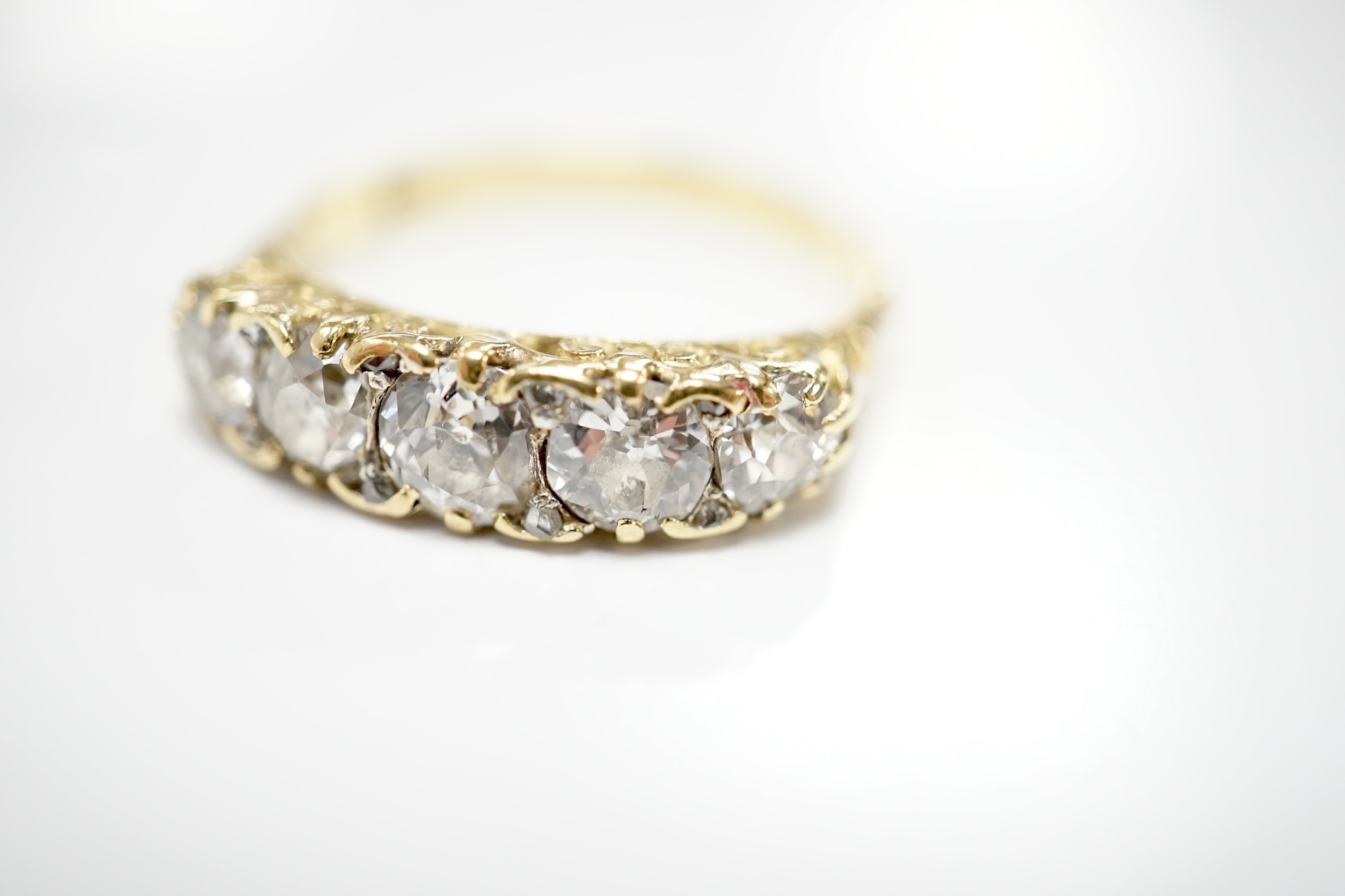 An early 20th century 18ct and graduated five stone diamond set half hoop ring, with rose cut diamond set spacers, size Q/R, gross weight 4 grams. Condition - poor to fair